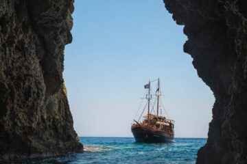 brown boat on body of water towards tunnel