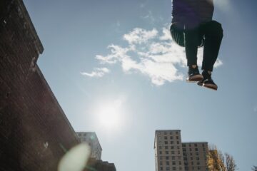 anonymous man jumping high near building