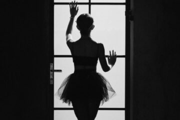 unrecognizable ballerina touching door in darkness