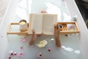 woman reading book while resting in bathtub