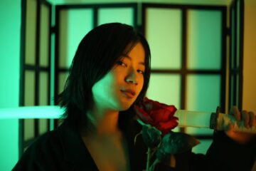 asian woman with katana and bright red blooming rose