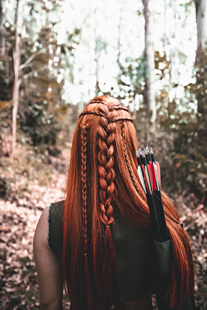 anonymous female warrior with bow and arrows in mystery forest