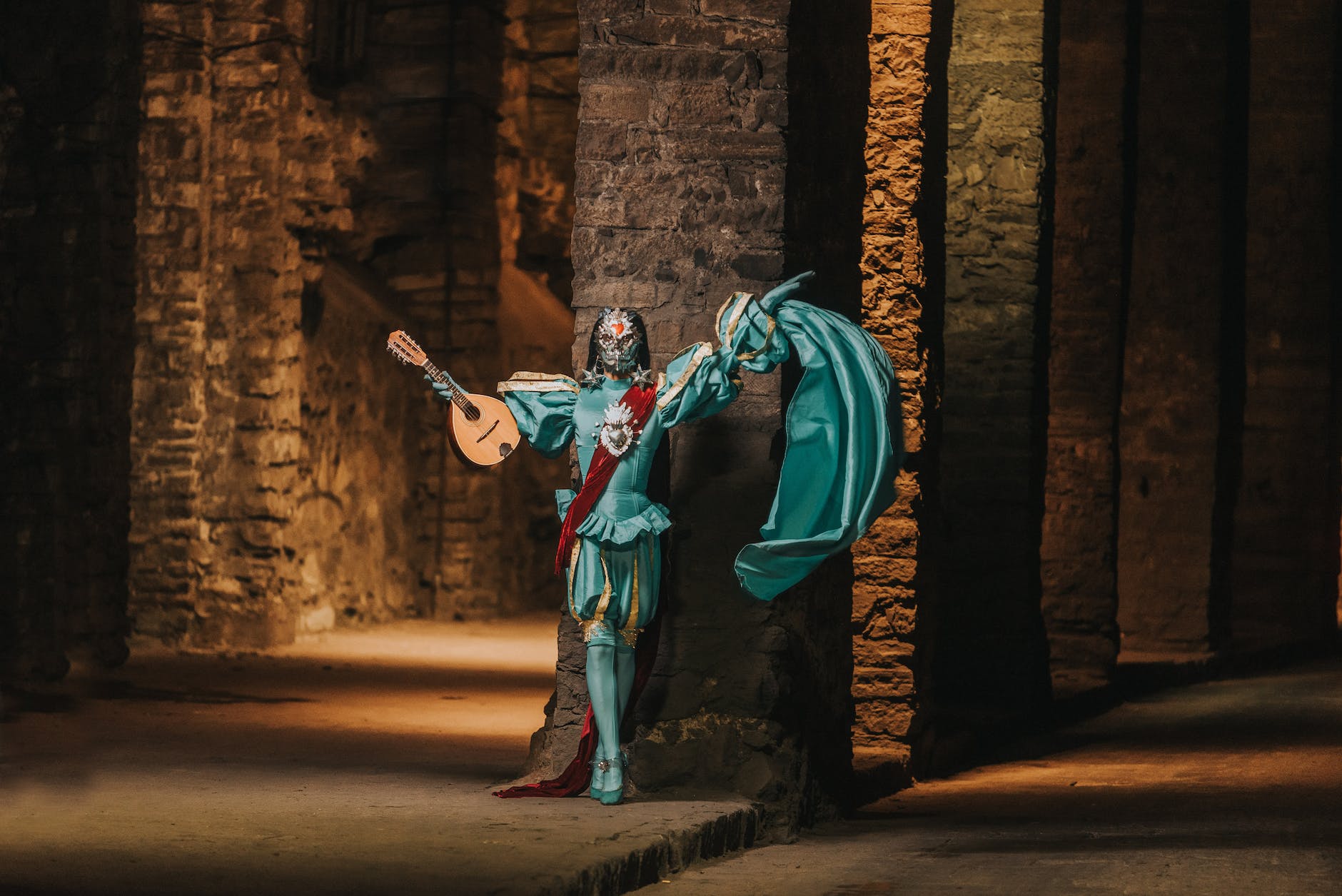 bard wearing face mask posing with lute in empty castle hallway