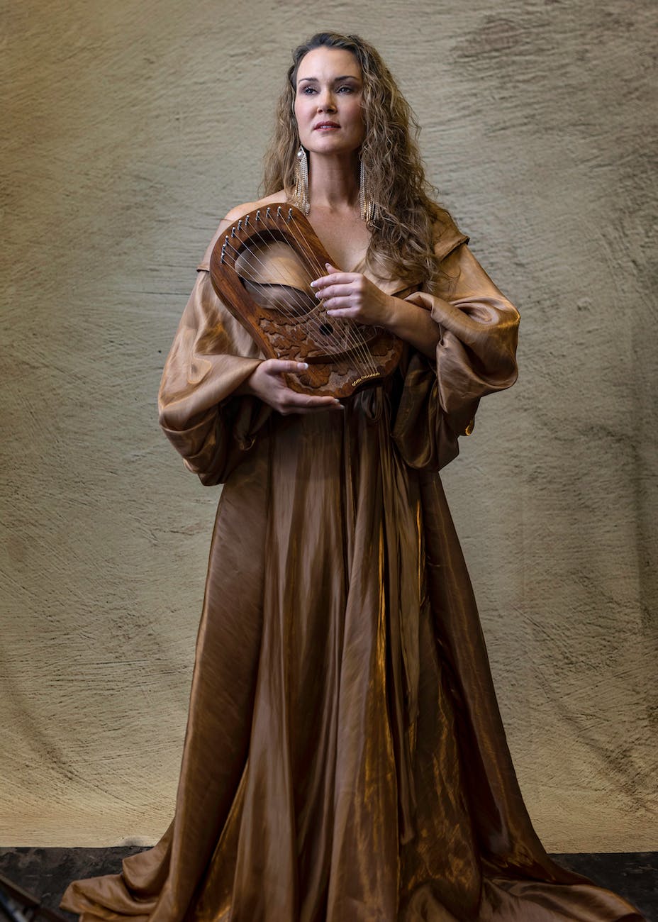 woman in long dress with lyre in hands
