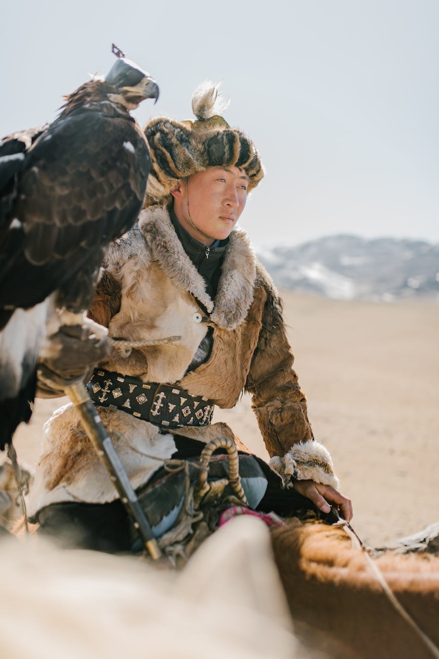 young mongolian man with eagle riding horse